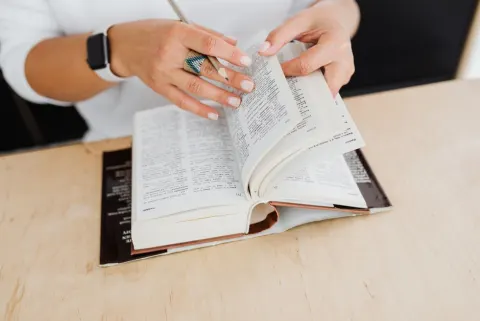 Femme qui tourne les pages d'un dictionnaire sur un bureau en bois